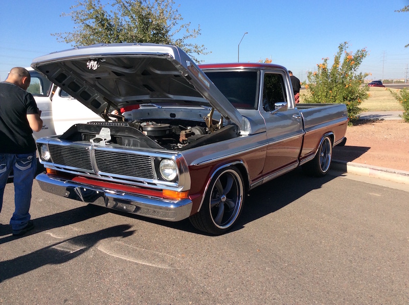 Two-tone pickup truck, maroon and silver, with hood open. Custom wheels