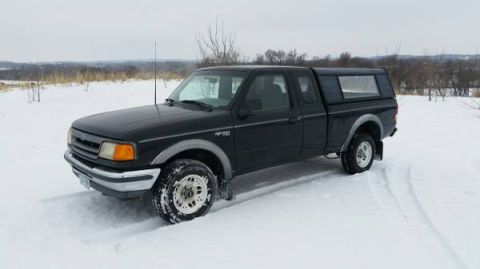1990 Ford Bronco - A black Ford Ranger pickup truck with a camper shell sits in a snowy field.