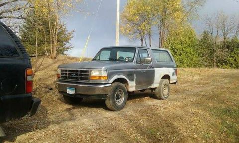 1990 Ford Bronco - A two-tone Ford Bronco is parked outdoors, with one side showing primer.
