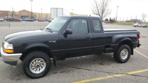 1990 Ford Bronco - This black Ford Ranger pickup truck is seen from the side in a parking lot.