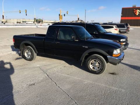 1990 Ford Bronco - A black Ford Ranger pickup truck is parked in a lot on a sunny day with other vehicles nearby.