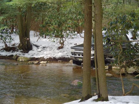 1993 Ford Bronco - 1993 Ford Bronco navigating a stream in a snowy, forested landscape.