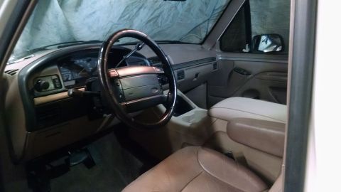 1994 Ford Bronco - The interior of a vehicle is shown, the dashboard, steering wheel, and seats.