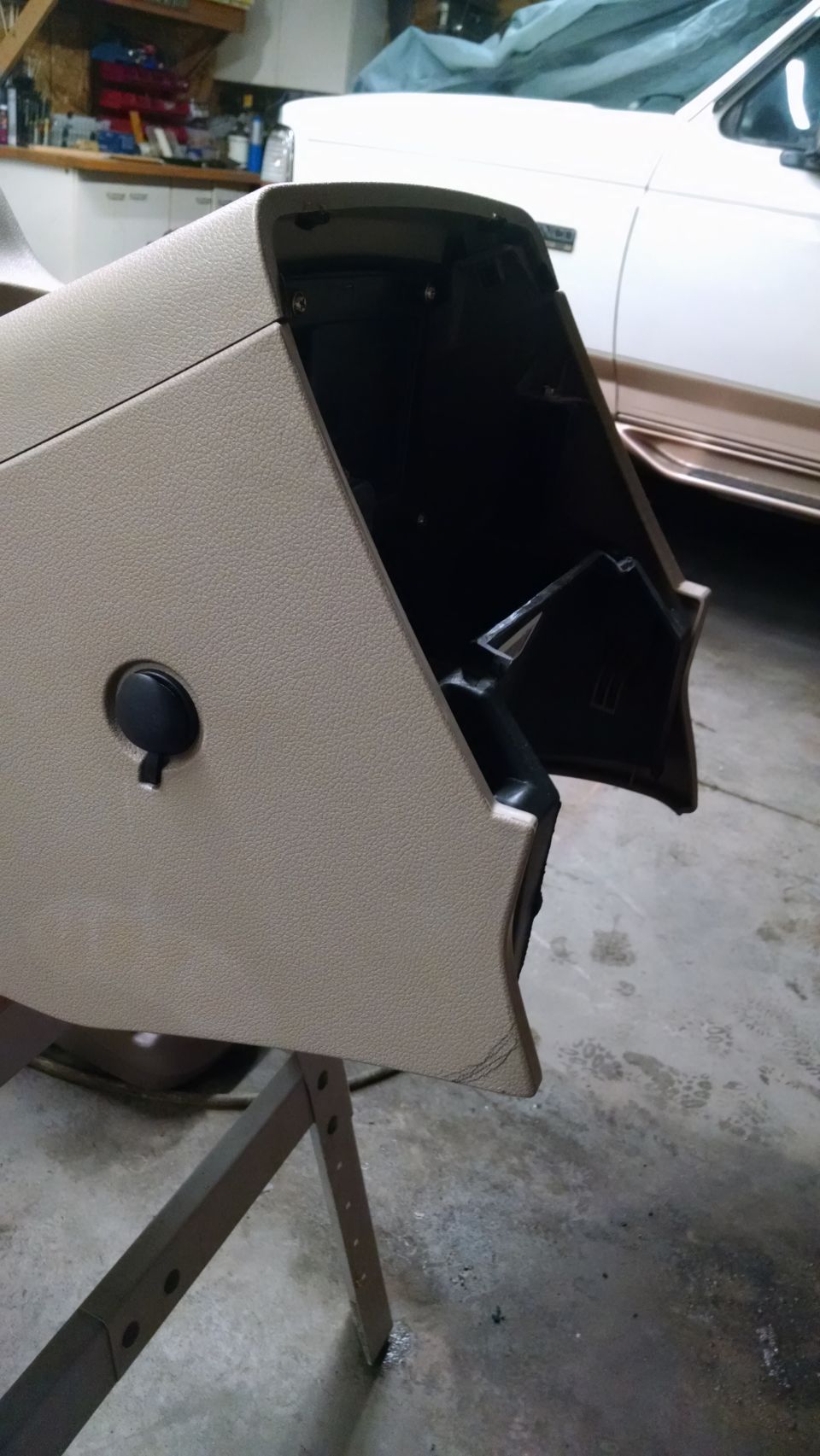 Tan textured glove box door removed from vehicle, showing interior cavity