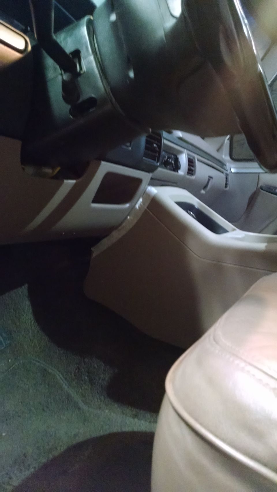 Tan interior of a 1992 Ford Bronco with a tan dashboard, center console, and seats. The steering wheel and floor mats are visible