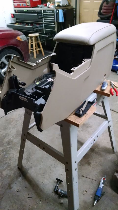 1994 Ford Bronco - Center console removed from a vehicle, likely for repair or modification, resting on sawhorses in a garage.