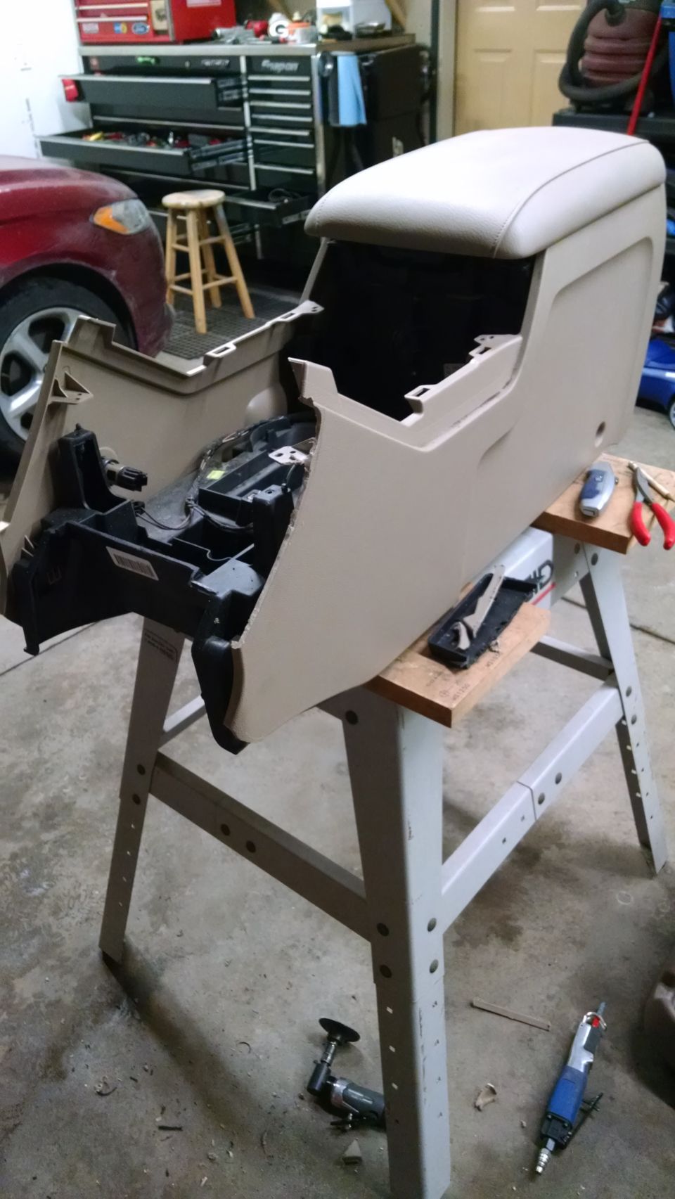 Tan center console removed from vehicle, resting on sawhorses