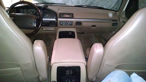 1994 Ford Bronco - The interior of a vehicle is shown, tan upholstery and a beige dashboard.