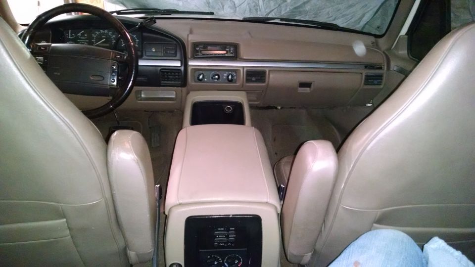 Interior view of a tan vehicle, showing dashboard, steering wheel, center console, and seats