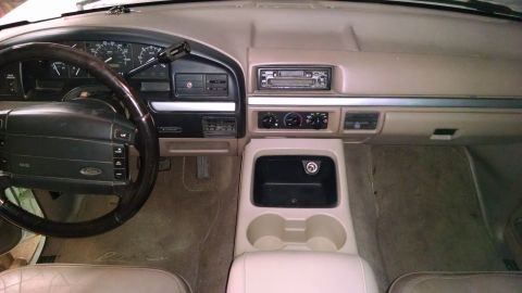 1994 Ford Bronco - The interior of a 1992 Ford Bronco shows a tan dashboard, steering wheel, and center console.