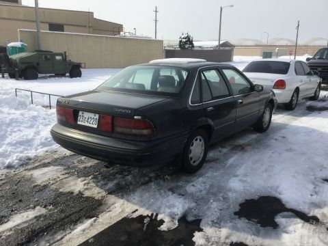 1995 Holden Astra - A dark sedan is parked in a snowy lot, showing its rear end and Daewoo badging.