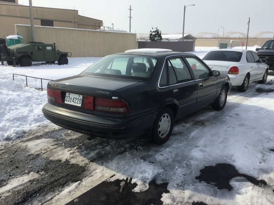 Dark sedan rear view with Daewoo badging and license plate 23-4220
