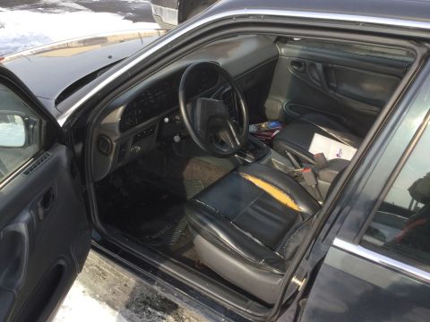 1995 Holden Astra - Interior view of a black car showing worn seats and dashboard details.