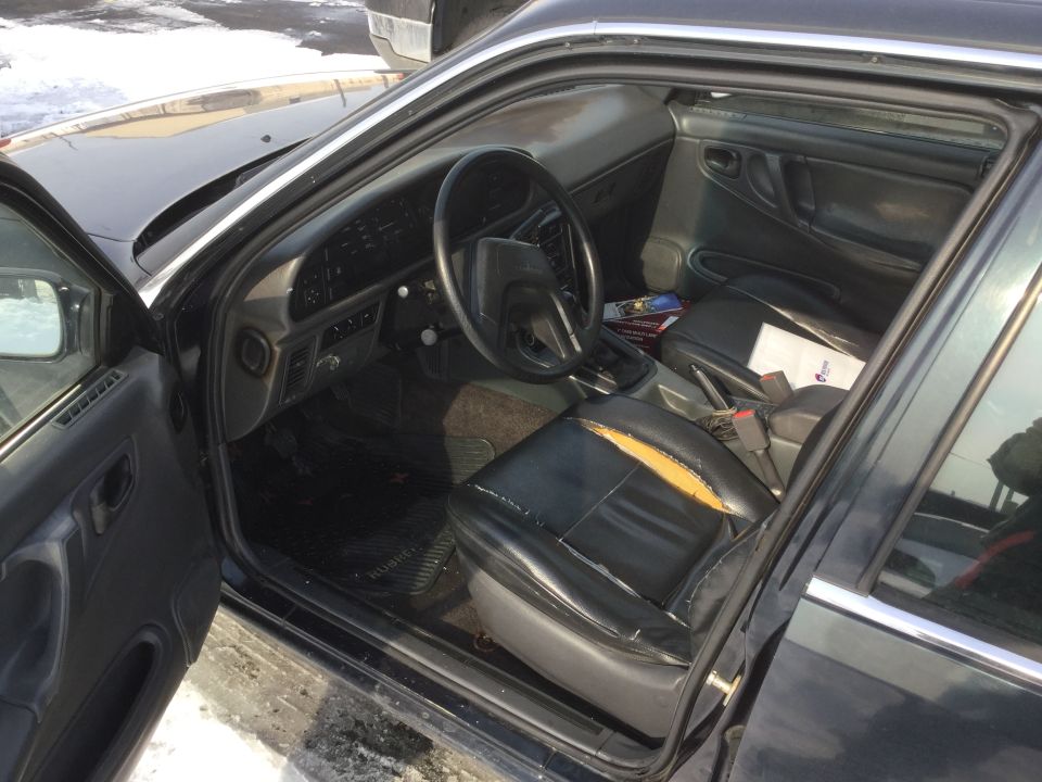 Black car interior with torn driver's seat, dashboard, and center console visible