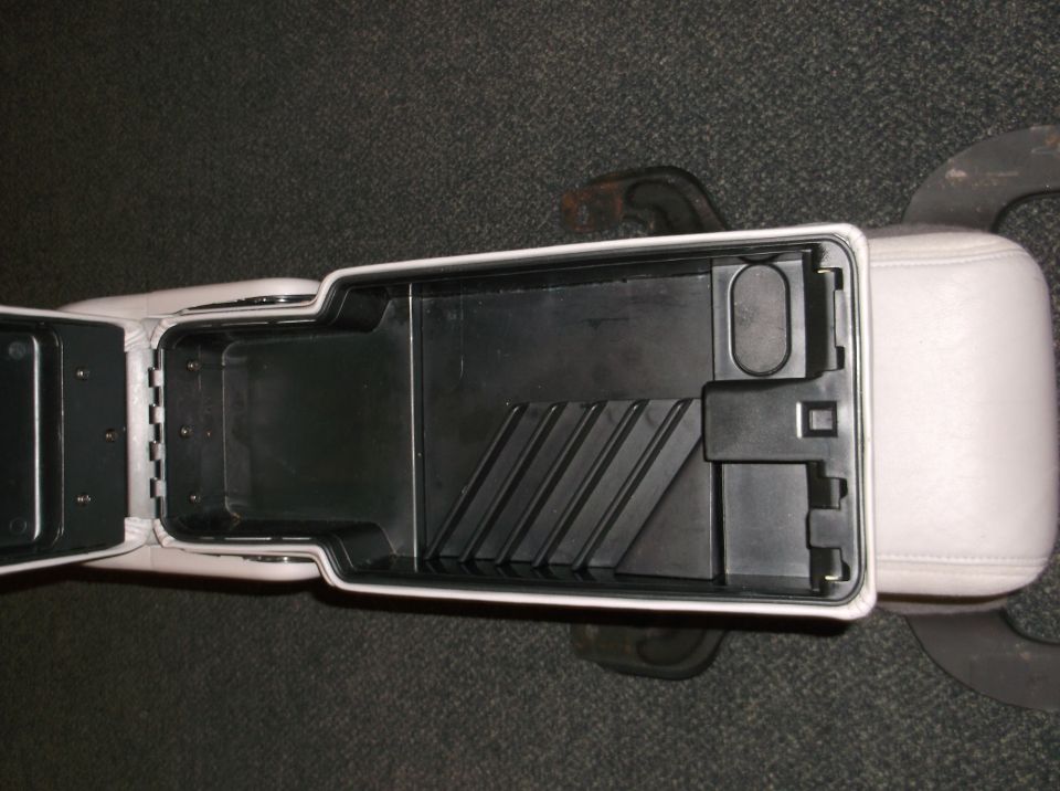 Open center console storage compartment with light-colored upholstery visible