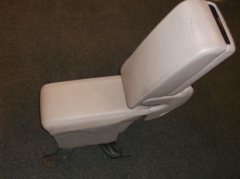 1999 Mercury Grand Marquis - A light gray center console armrest, likely from a car, is shown from an elevated angle. The part features visible stitching and a small bl…