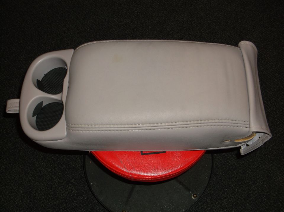 Gray leather center console with dual cup holders, resting on a red object
