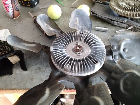 1992 Ford Bronco - A fan clutch and fan blades are laid out on a workbench, possibly for repair or replacement.