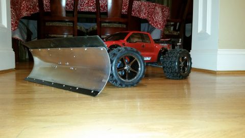 1994 Ford Bronco - A red remote control truck is equipped with a large, silver snow plow attachment.