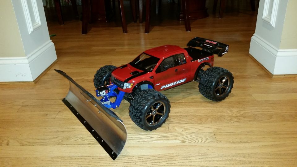 Red RC monster truck with snow plow attachment