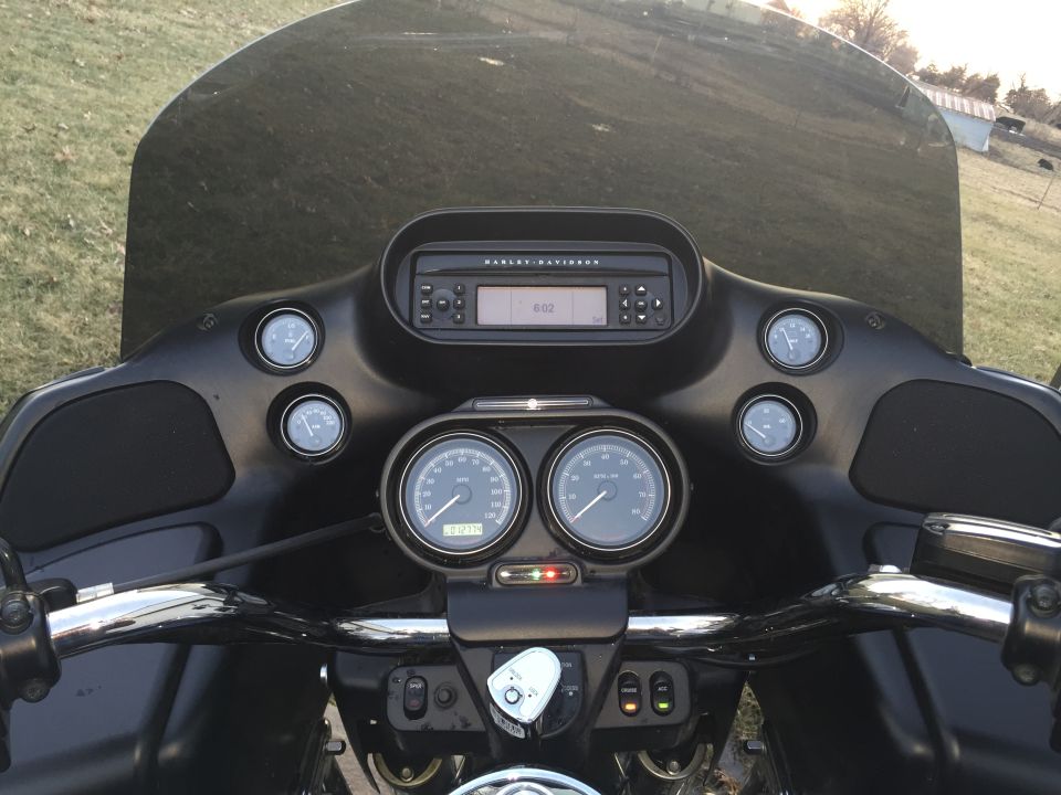 Motorcycle dashboard with two large gauges, a radio, and a tinted windshield. The gauges show 0 miles