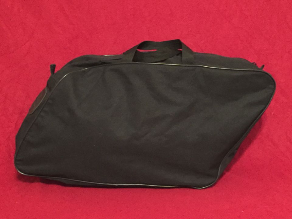 Black motorcycle saddlebag on a red background. Supermotors.net logo in the lower right