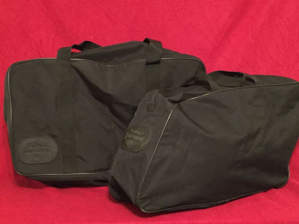 Two black Harley-Davidson saddlebags on a red background