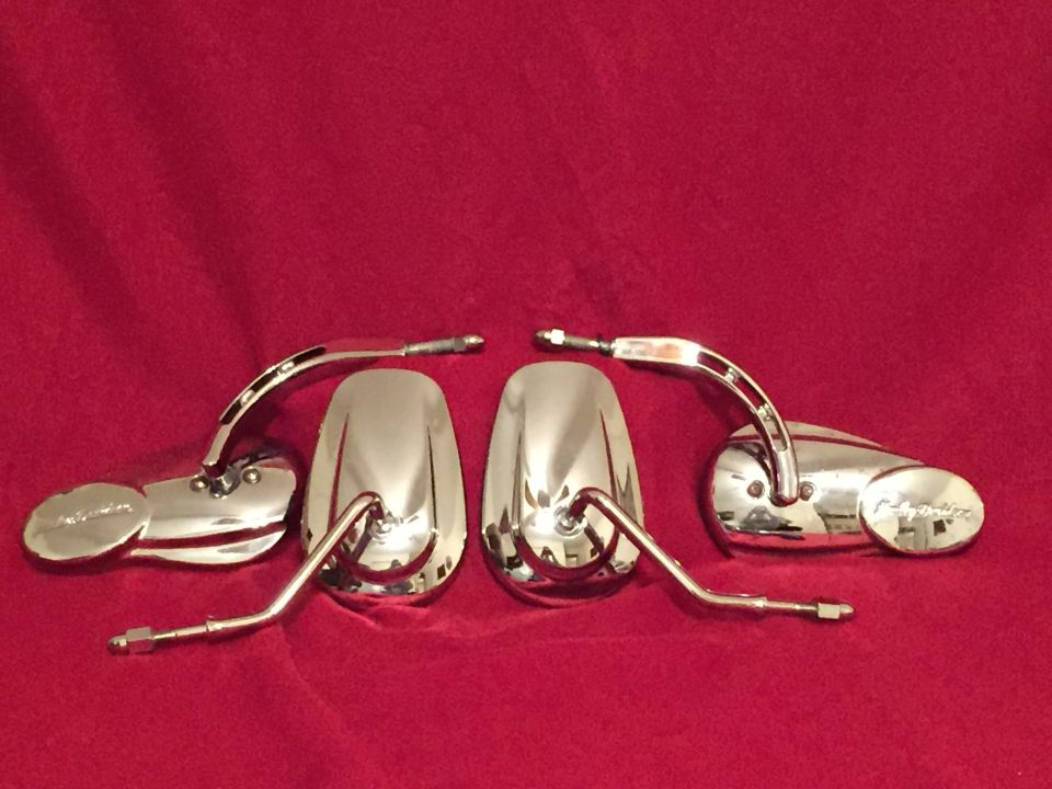 Two pairs of chrome motorcycle mirrors on a red background. Text on one mirror housing reads 'Harley-Davidson'