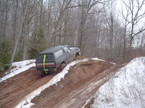 1993 Ford Bronco - This SUV, likely a 1992 model, struggles on a challenging off-road trail with mud and snow.