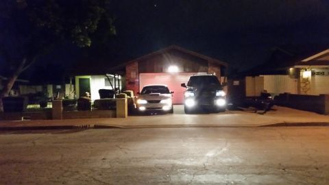2003 Ford Crown Victoria - silver sedan and a dark SUV with bright headlights sit in a driveway in front of a single-story house at night.