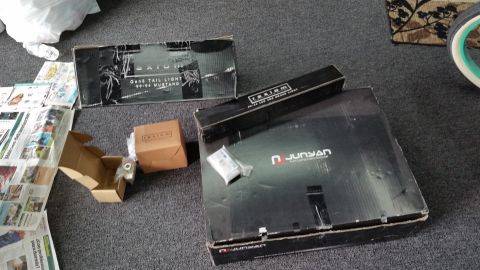 2002 Ford Mustang - Boxes containing Axiom tail lights and a Junyan LED brake light, labeled for a 1999-2004 Ford Mustang, are shown on a carpeted floor.