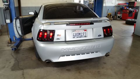 2002 Ford Mustang - A silver 2002 Ford Mustang is shown on a lift in a garage, with its driver's side door ajar.