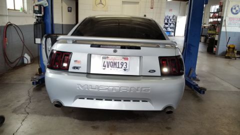 2002 Ford Mustang - Rear view of a silver 2002 Ford Mustang on a car lift in a repair shop.