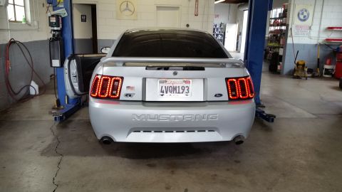 2002 Ford Mustang - This silver 2002 Ford Mustang features custom LED taillights and a GT badge, seen from the rear in a garage setting.
