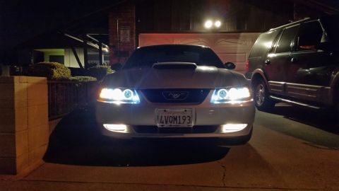 2002 Ford Mustang - A white 2002 Ford Mustang is parked in a driveway at night, its custom halo headlights and hood scoop.