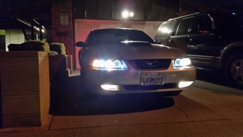 2002 Ford Mustang - Front view of a 2002 Ford Mustang with custom headlights parked at night next to an SUV.