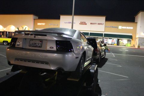 2002 Ford Mustang - A silver 2002 Ford Mustang is loaded onto a trailer at night in a parking lot.