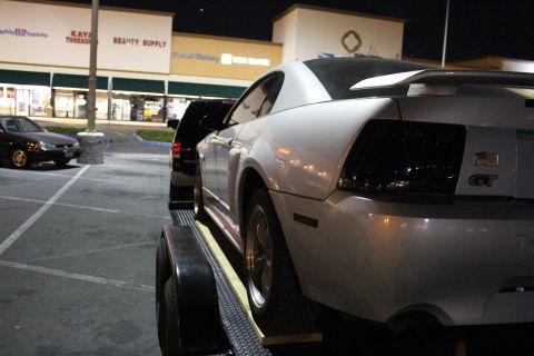 2002 Ford Mustang - Silver 2002 Ford Mustang GT on a trailer at night, with a black vehicle behind it.