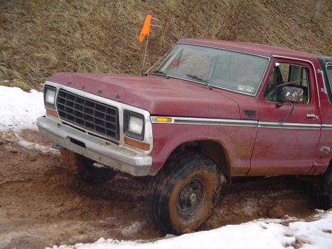 1993 Ford Bronco - This red Ford Bronco is navigating a muddy and snowy off-road trail.