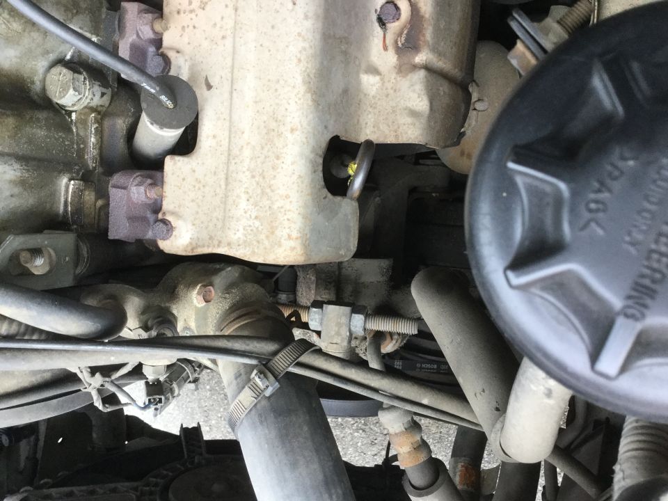 Close-up of engine bay with hoses, metal components, and a black cap labeled 'POWER STEERING'