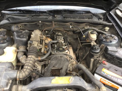 1995 Holden Astra - Engine bay of a 1995 Holden Astra, revealing its mechanical components and a visible battery.