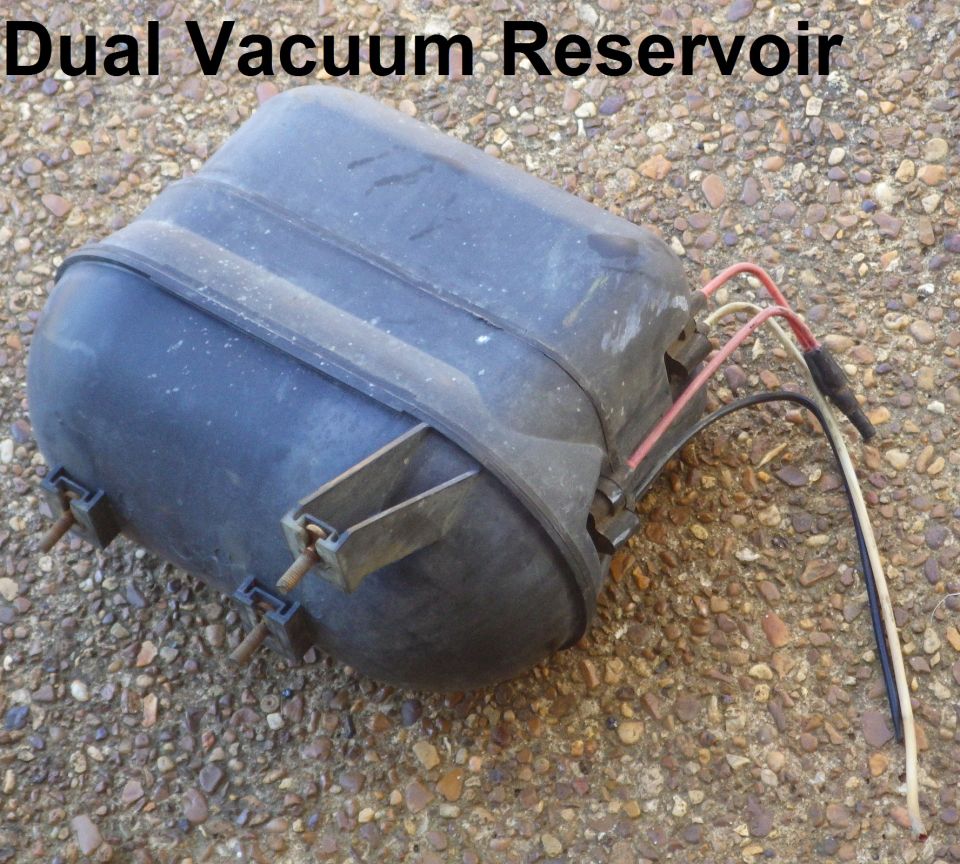 Dusty black dual vacuum reservoir with colored lines lying on gravel.