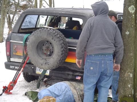 1993 Ford Bronco - Ford Bronco with spare tire and Hi-Lift jack, people working in the snow.