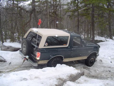 1993 Ford Bronco - This Ford Bronco is navigating a snowy, wooded area with large rocks.