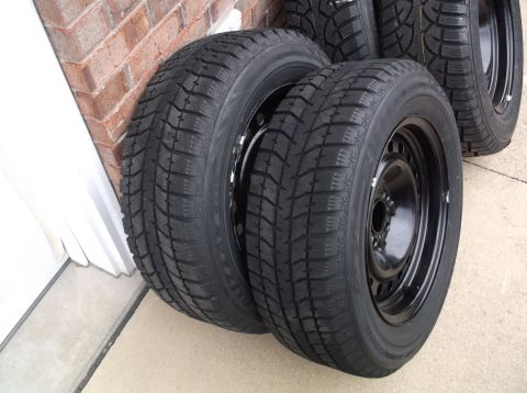 1999 Mercury Grand Marquis - A set of four winter tires mounted on black steel wheels are shown leaning against a brick wall.
