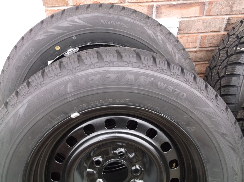 Stack of four Bridgestone Blizzak WS70 tires on black steel wheels