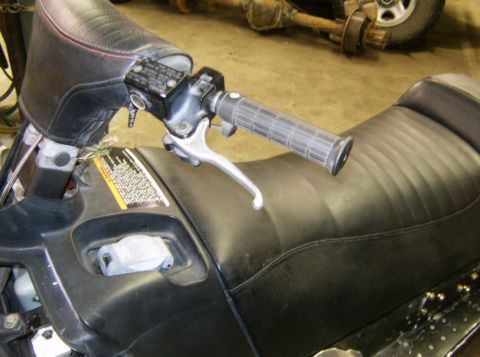2000 Ford E350 - Close-up of snowmobile controls and seat, with a vehicle axle in the background.