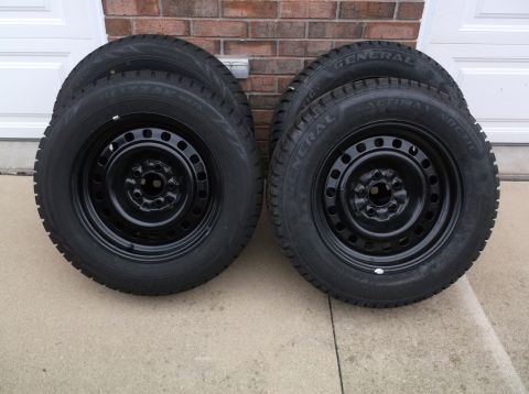 1999 Mercury Grand Marquis - Four steel wheels with winter tires are displayed in front of a brick wall and garage door.