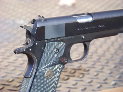 1995 Mercury Grand Marquis - A close-up view of a Colt Government Model pistol, showing the slide serrations and checkered grip.