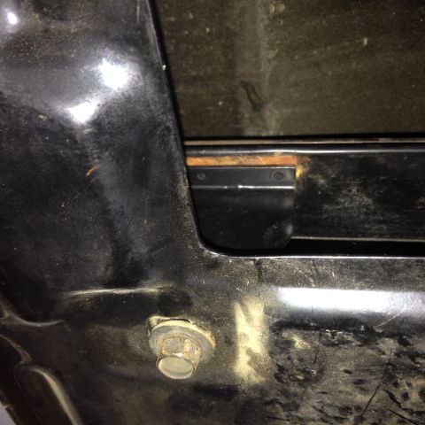 1993 Ford Bronco - A close-up view of a bolt and bracket on the underside of a vehicle, showing some rust.